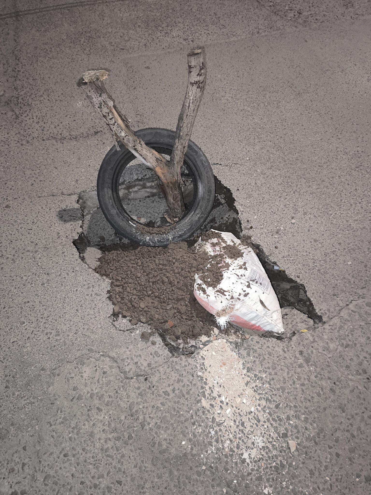 Socavón en calle residencial señalizado con llanta y palos — México